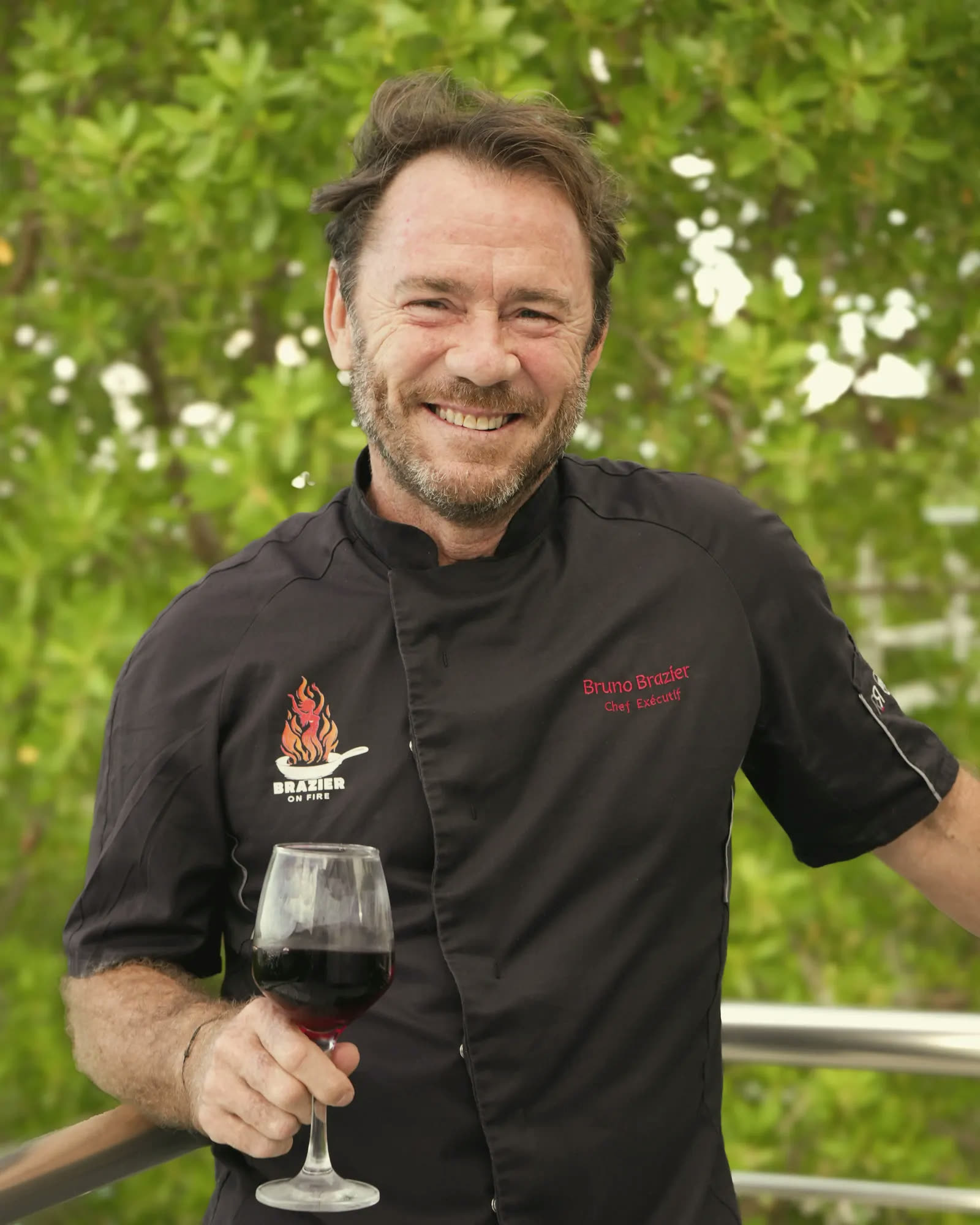 Bruno Brazier in his chef’s jacket, holding a glass of red wine